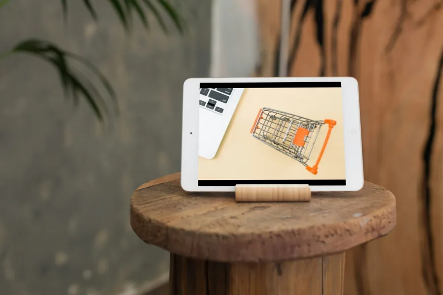 Tableta mostrando un carrito al lado de un portátil, representando gestión tiendas online
